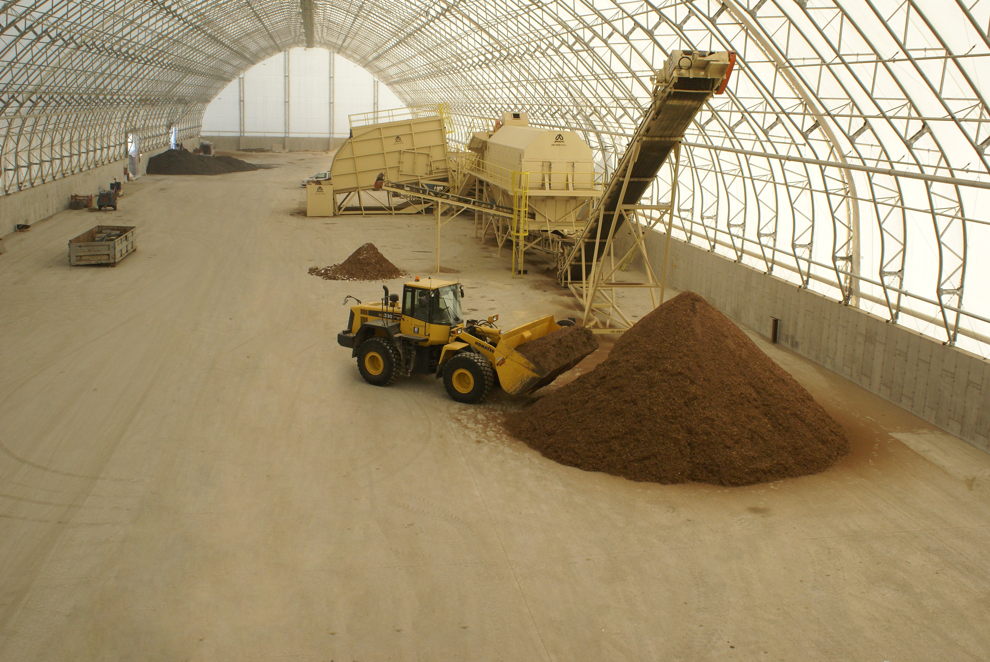 Front-end loader inside an industrial composting fabric building